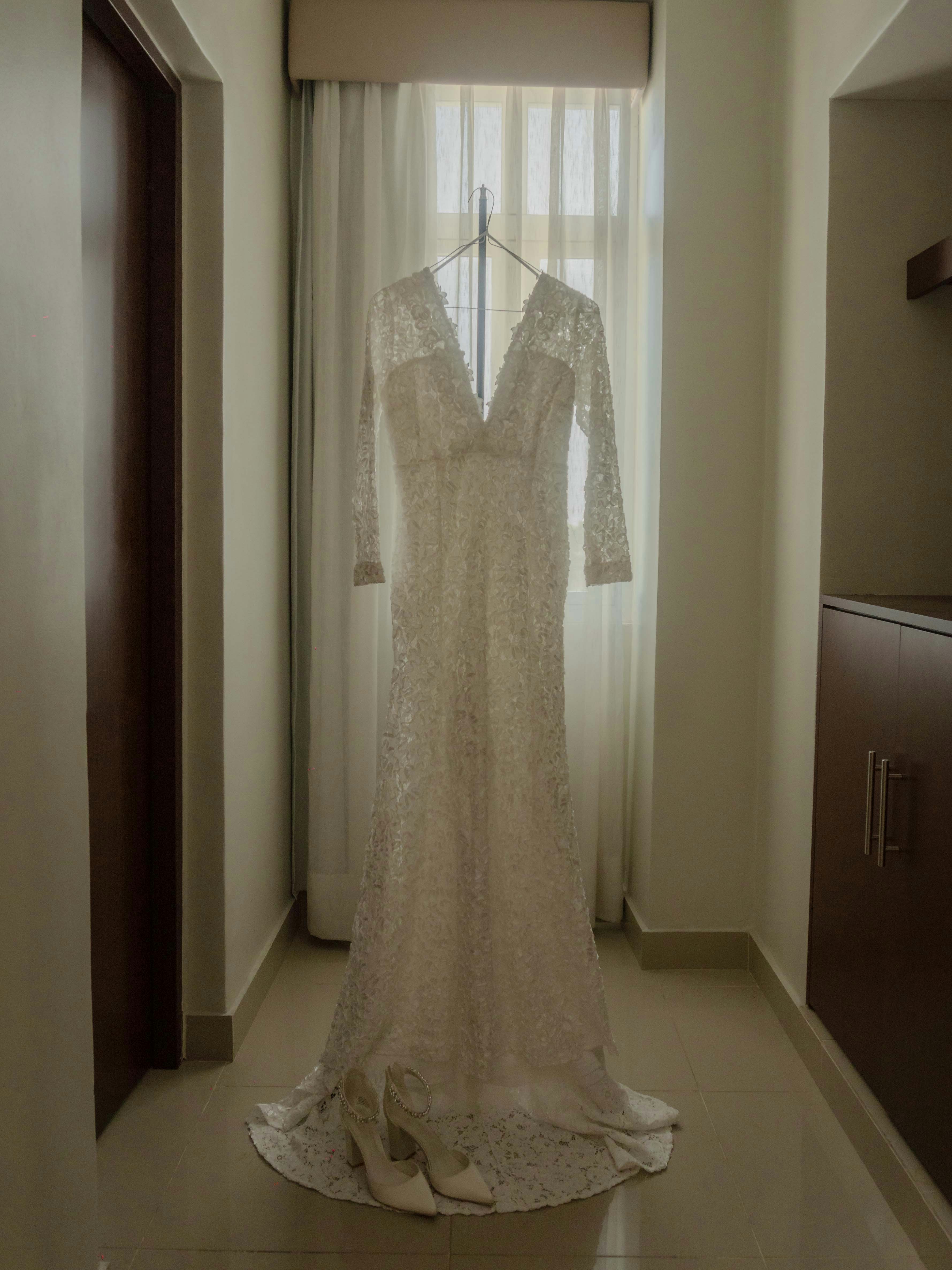 a wedding dress hanging in front of a window