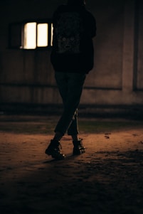 a person standing in the dark with a skateboard