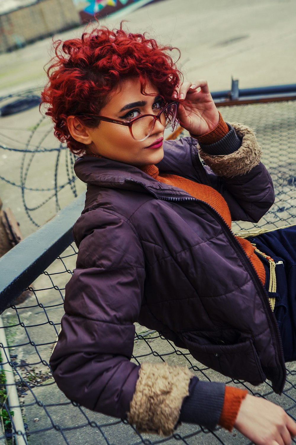 a woman with red hair and glasses sitting on a bench