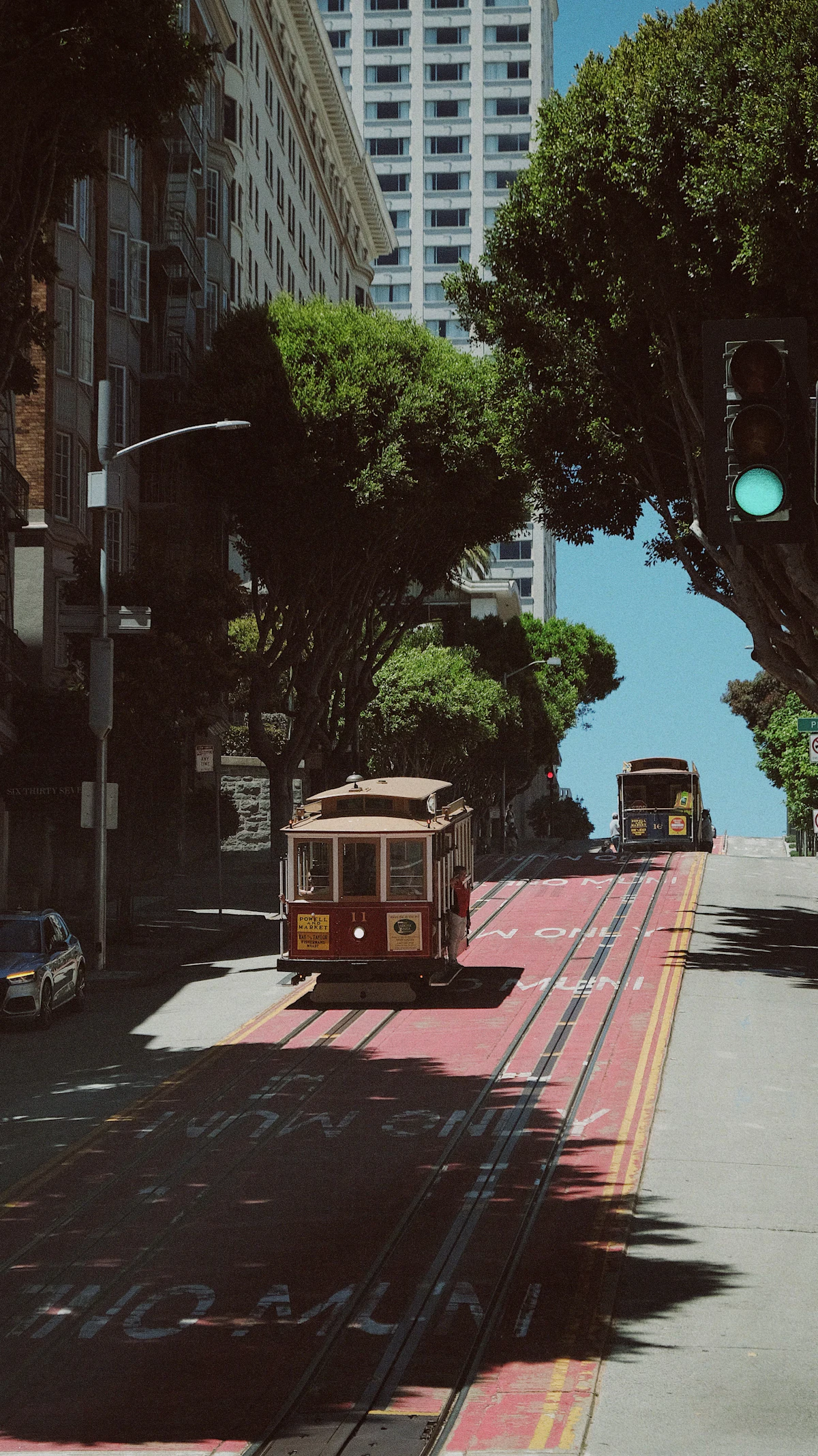A San Francisco cable car traveling down a tree-lined street