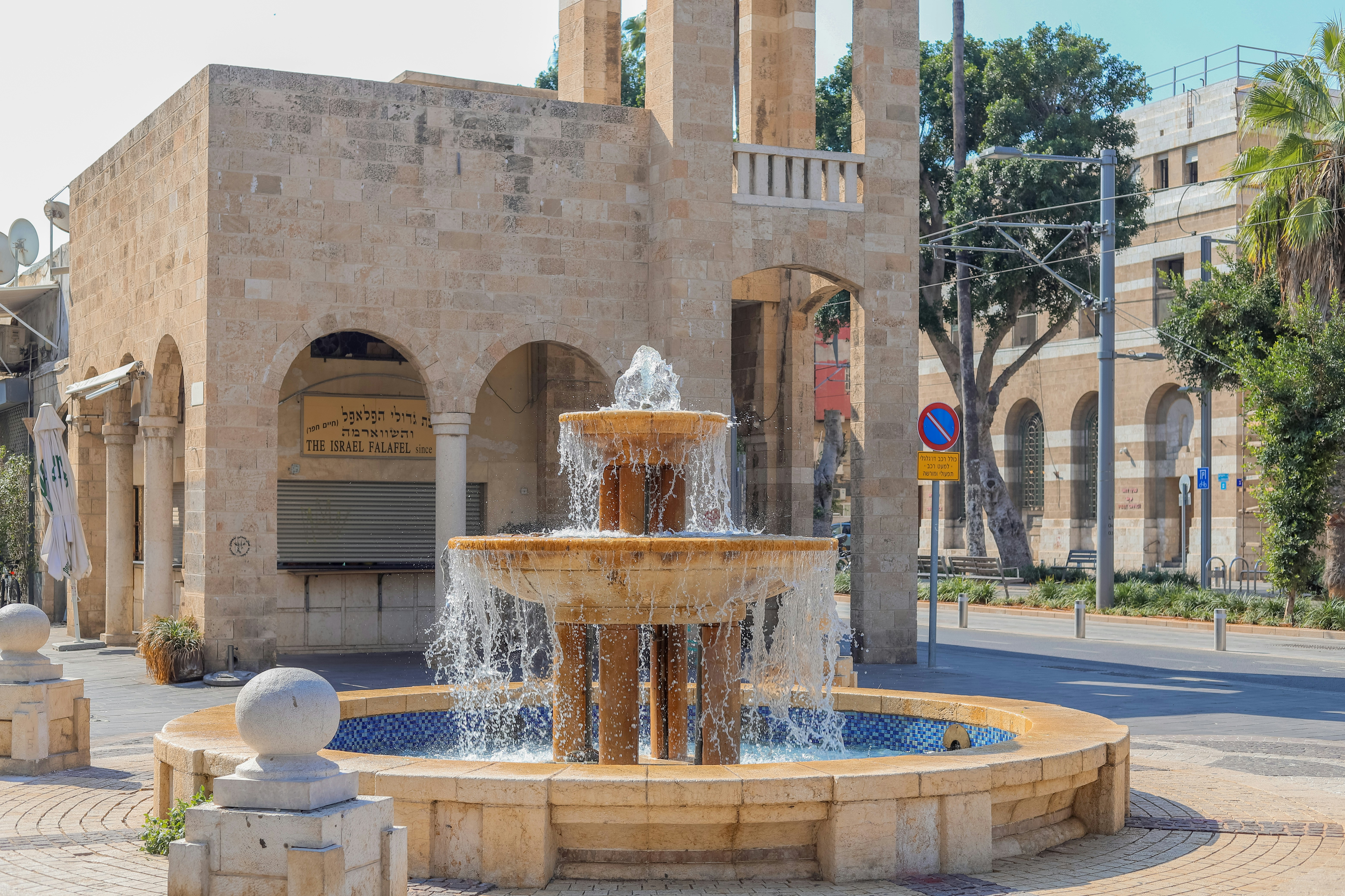 a fountain in front of a building with a clock tower in the background
