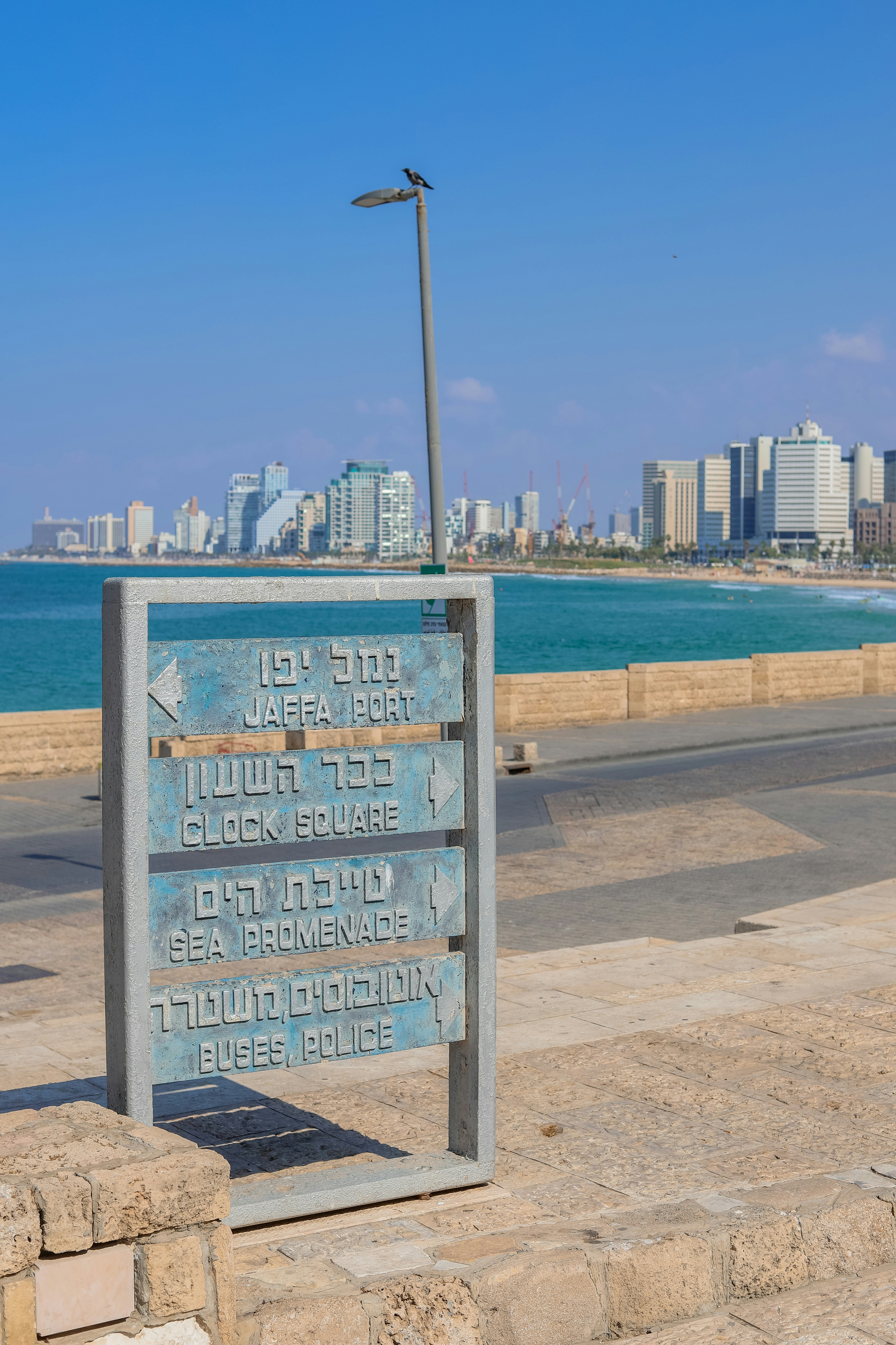 a sign in front of a body of water with a city in the background