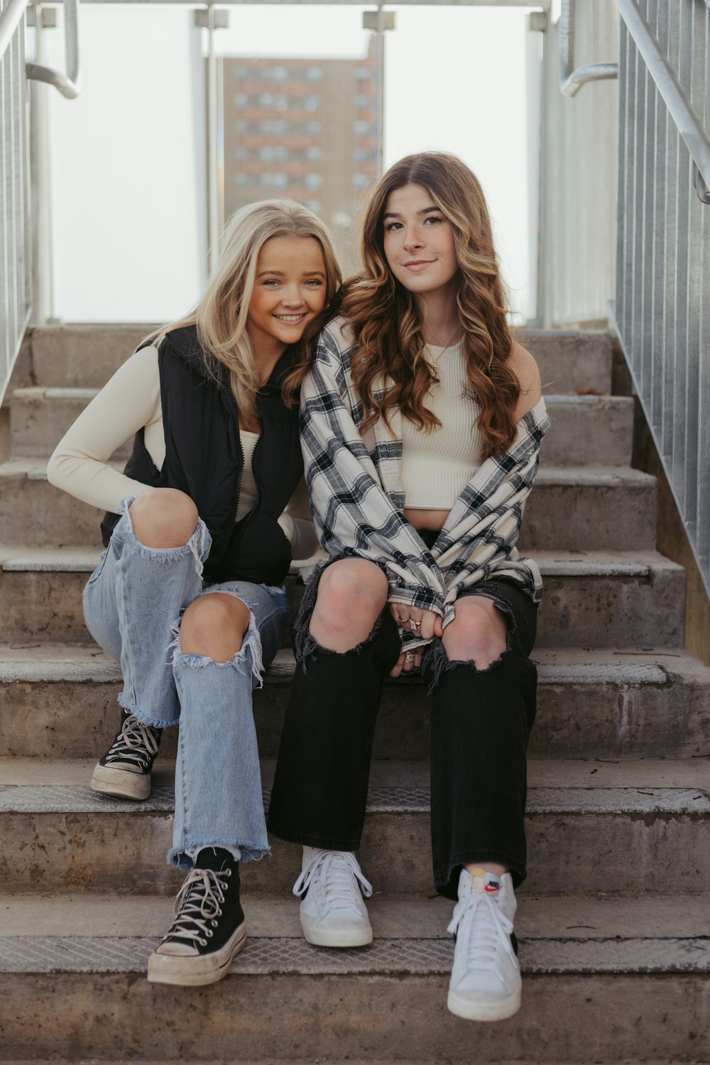 two women sitting on the steps of a building