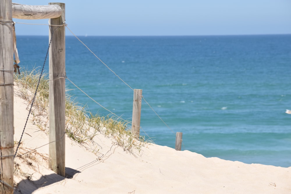 a wooden fence on a beach next to the ocean