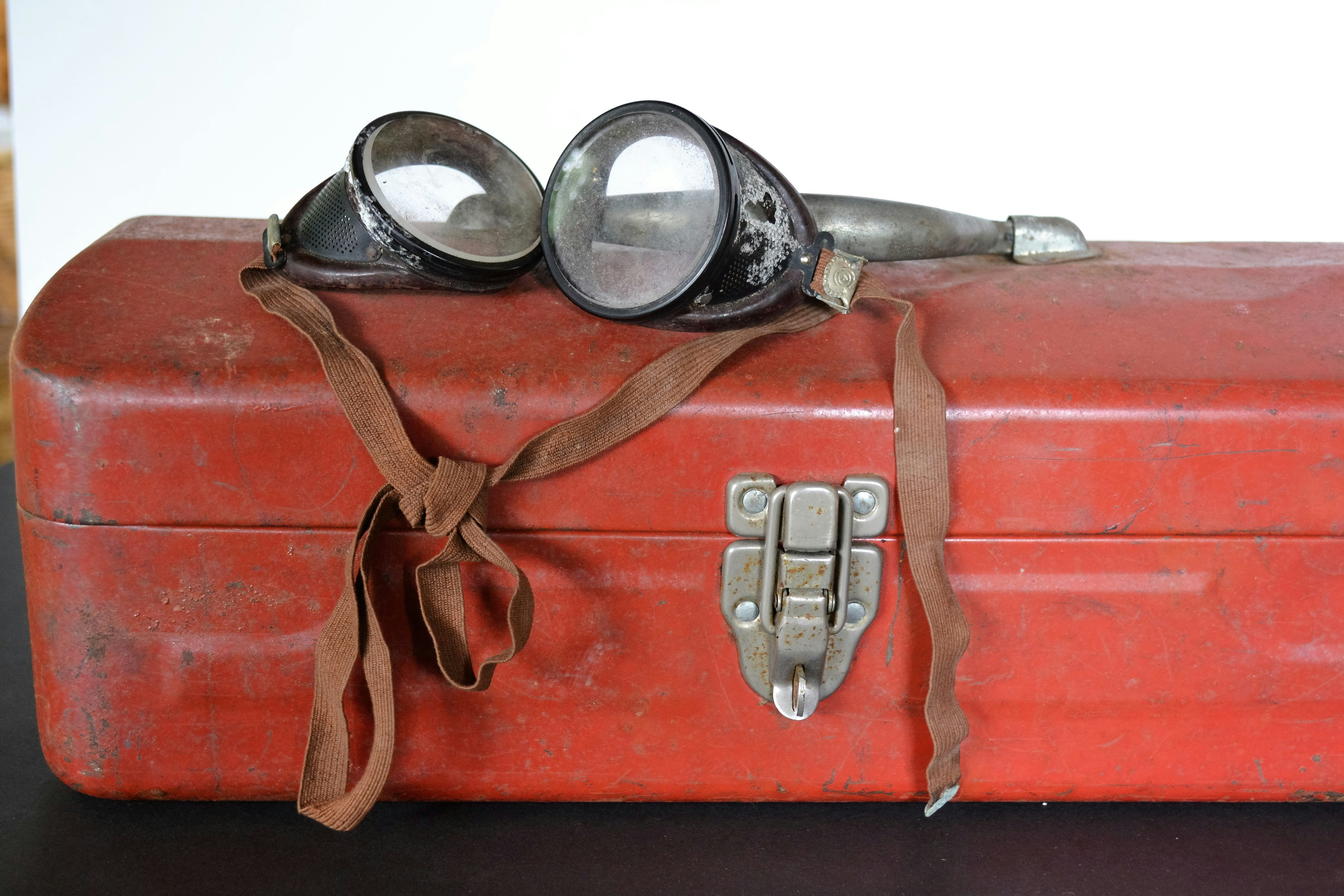 a pair of goggles sitting on top of a red suitcase