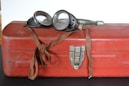 a pair of goggles sitting on top of a red suitcase