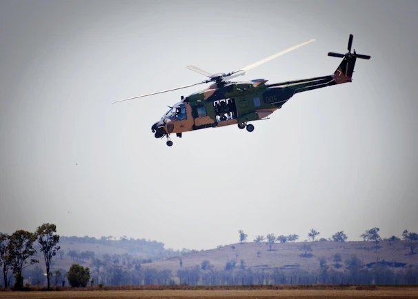 A helicopter hovering above a lush green landscape during a test flight.