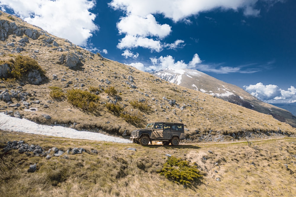 a jeep driving down a dirt road in the mountains