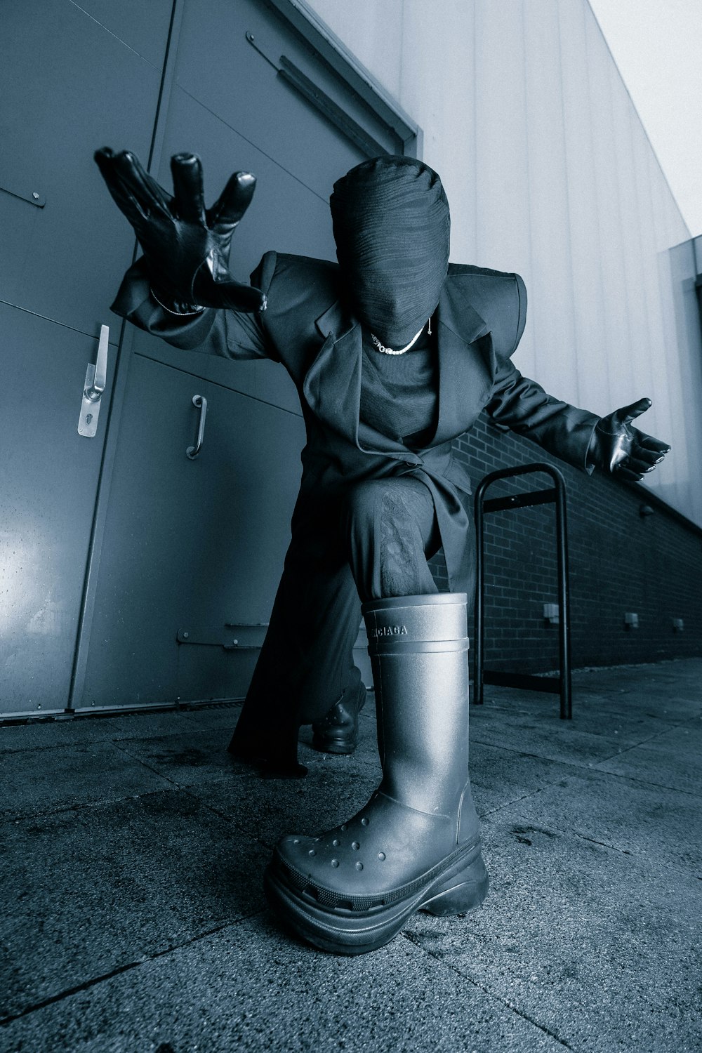 a man in a suit and rubber boots sitting on a chair