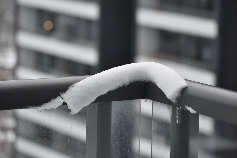 a snow covered balcony railing with a building in the background
