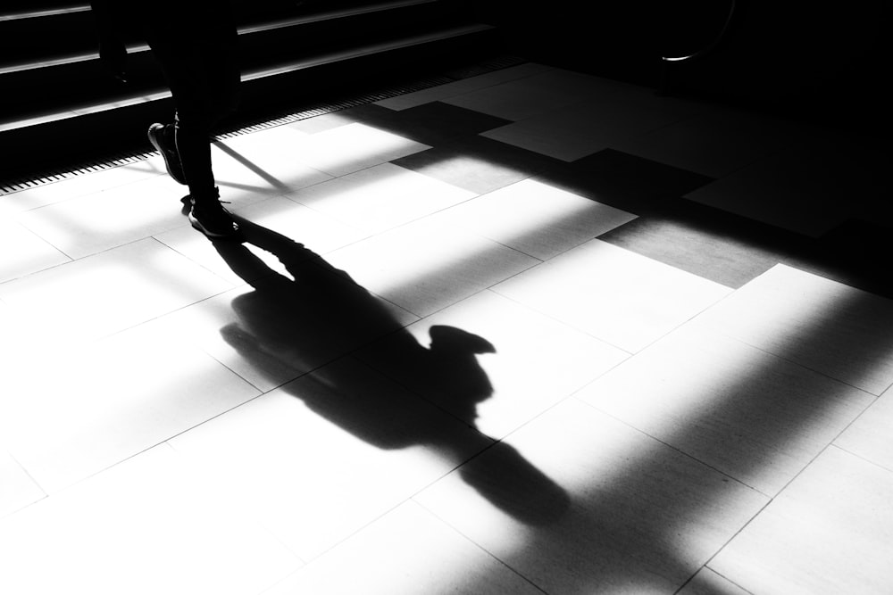 a shadow of a person standing on a tiled floor