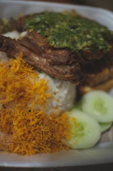 A colorful plate of jerk chicken with rice and peas, garnished with fresh herbs.