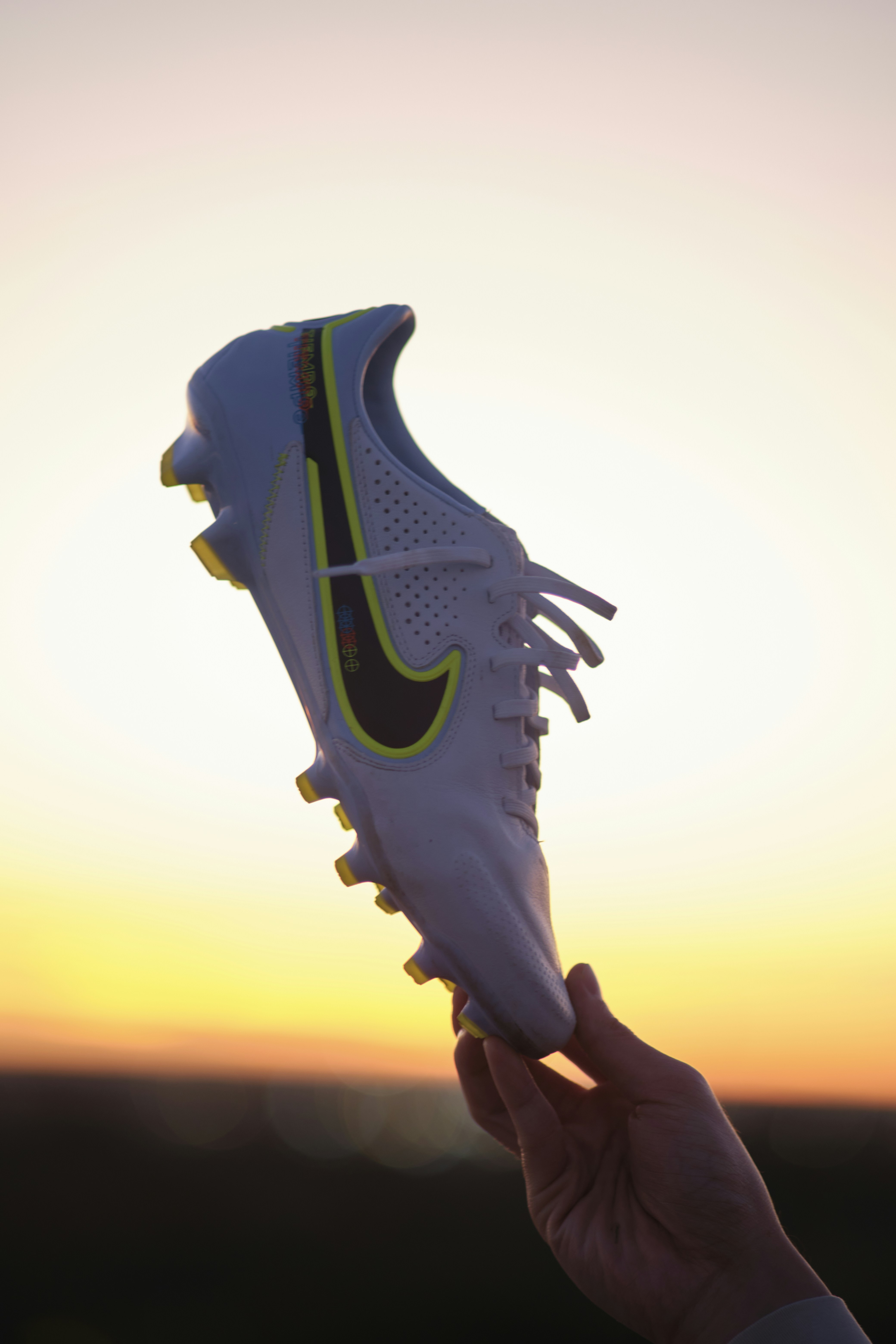 a person holding up a pair of white shoes