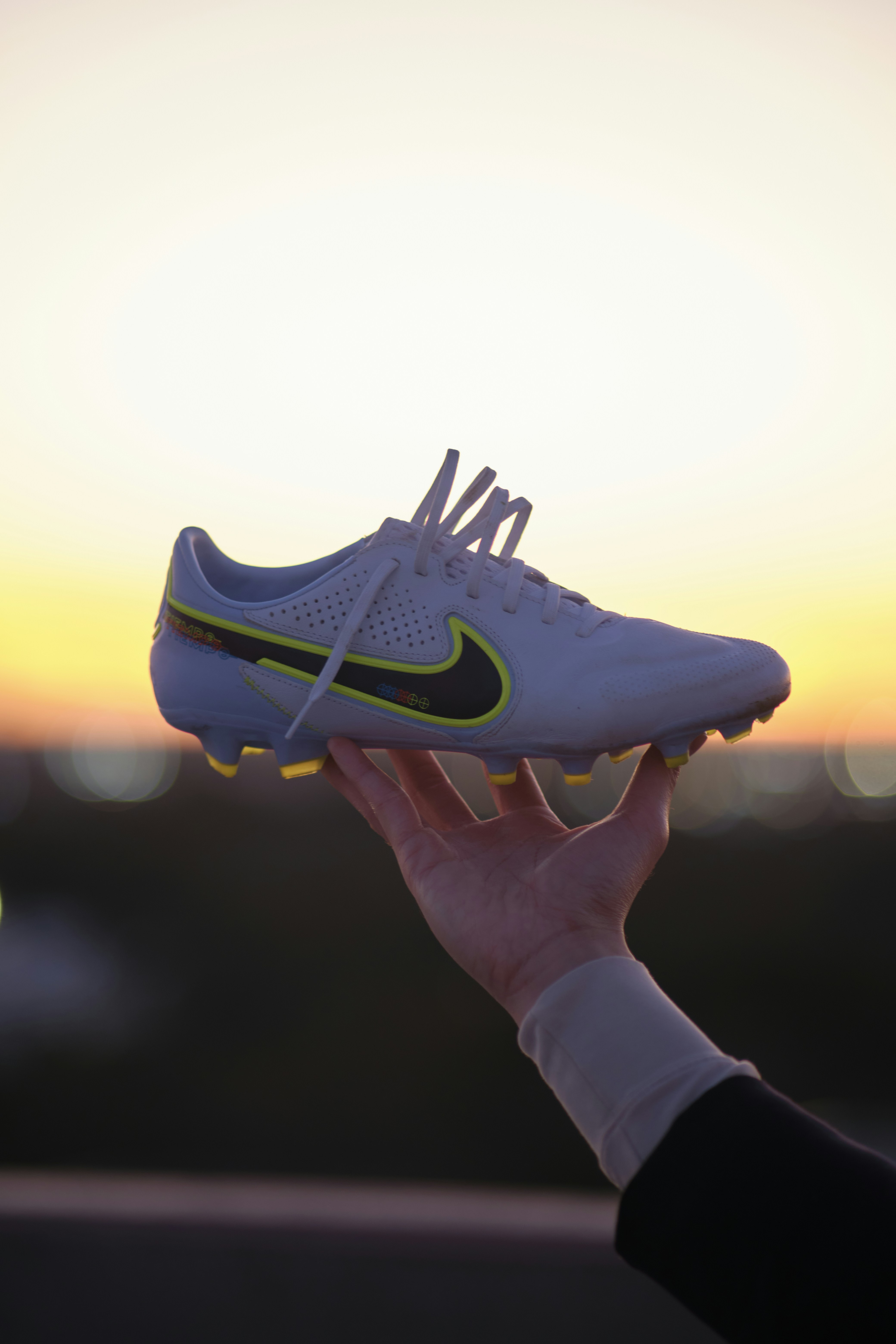 una persona che tiene una scarpa davanti a un tramonto