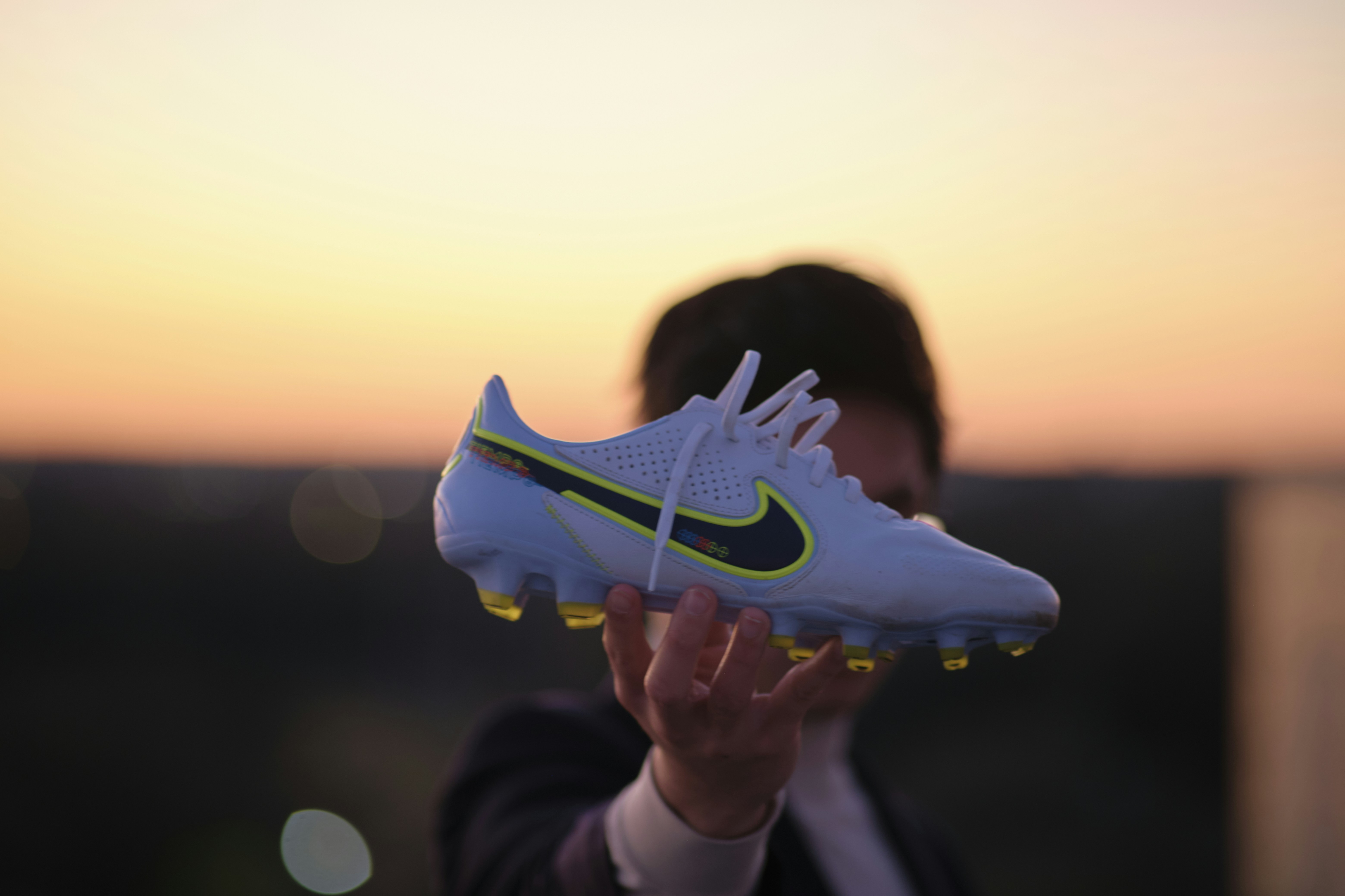 a person holding a shoe in front of a sunset