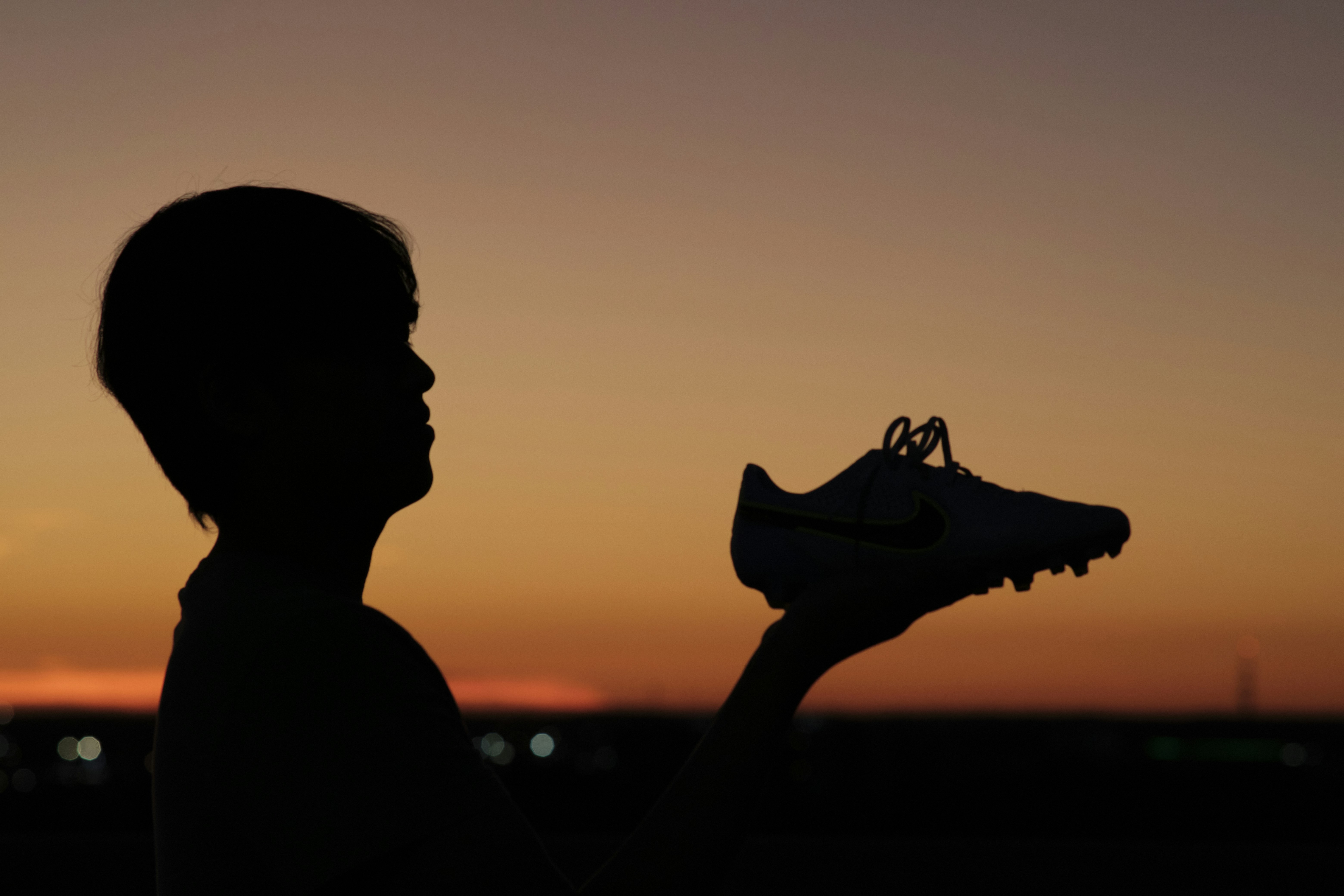 eine Silhouette einer Person, die ein Paar Schuhe hält