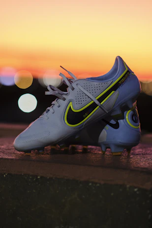 A vibrant display of football gear including cleats, jerseys, and balls arranged on a field background under bright stadium lights.
