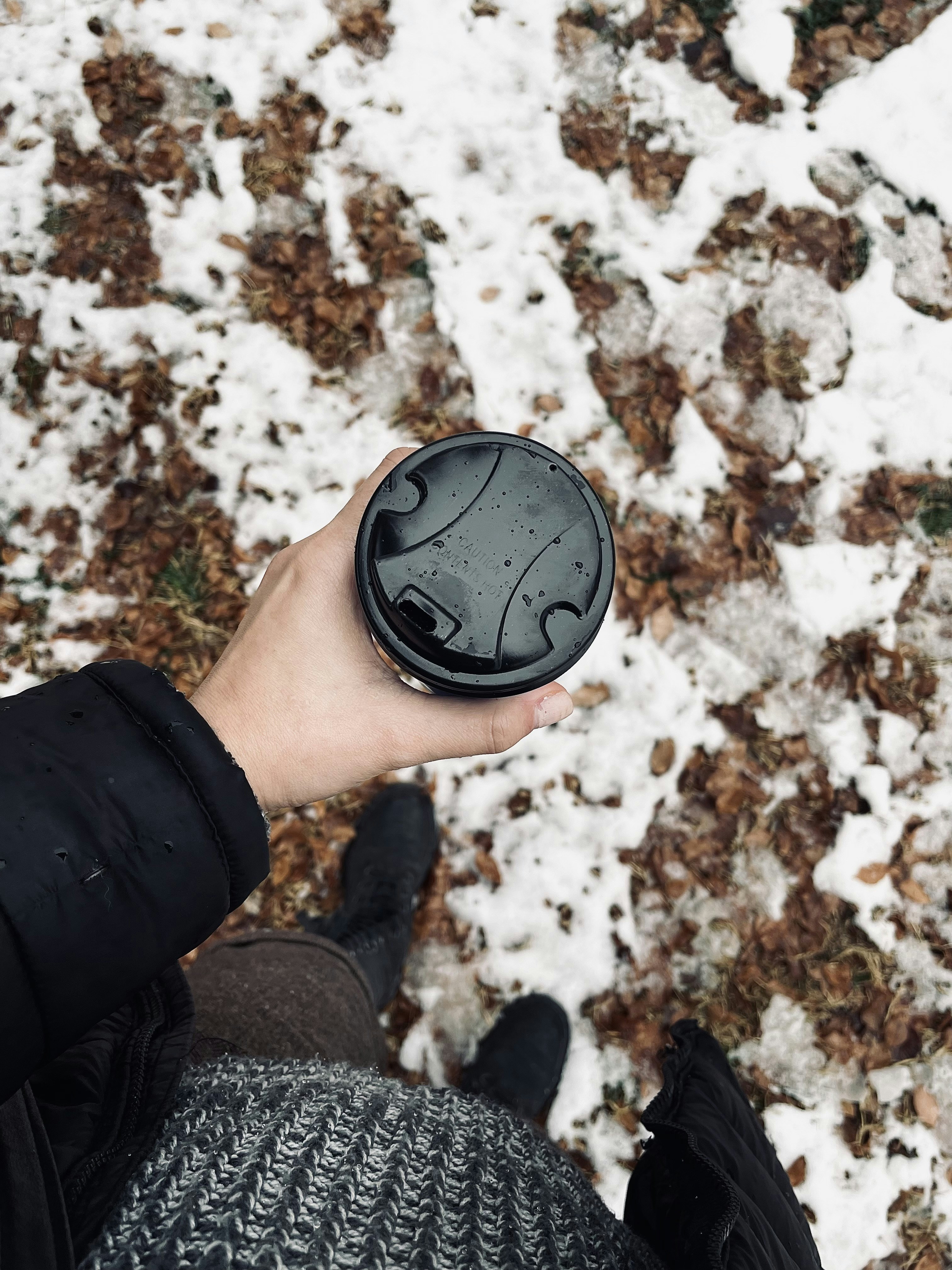 a person holding a cup in their hand in the snow