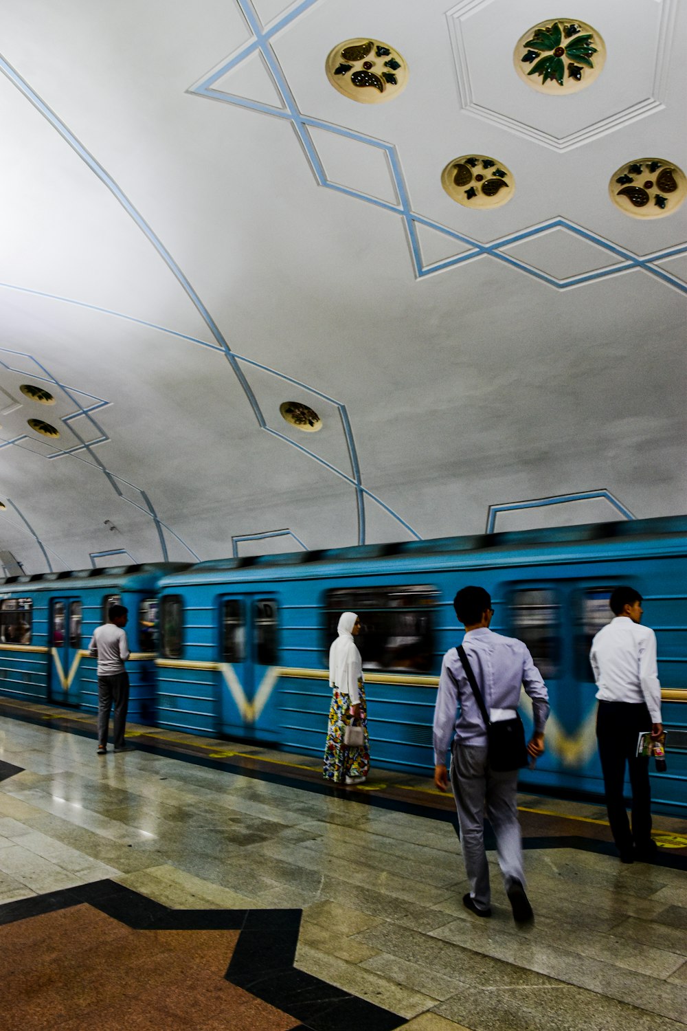 a group of people standing next to a blue train