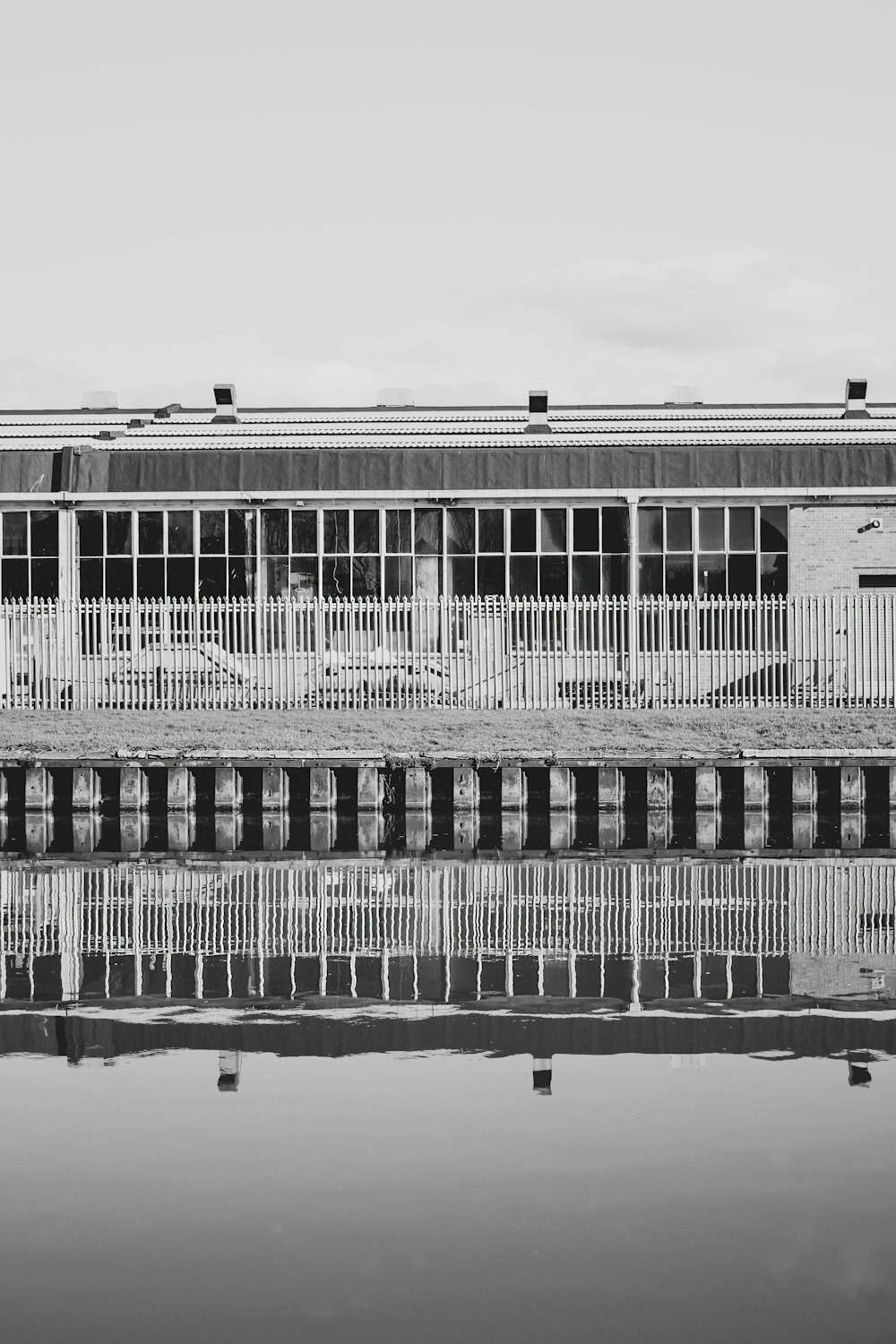 a black and white photo of a building next to a body of water