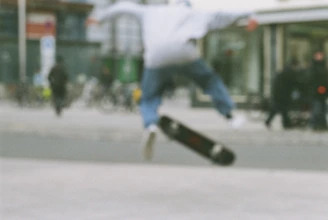 Dynamic action shot of a skater grinding a rail with the city skyline blurred behind.