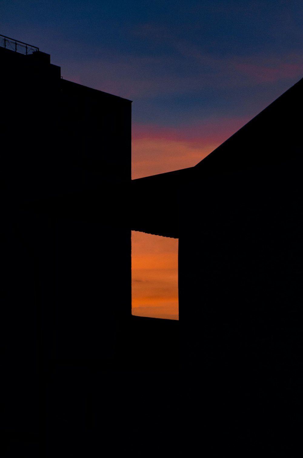the silhouette of two buildings against a sunset