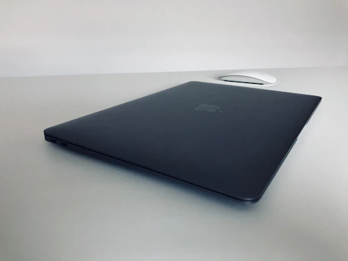 A sleek refurbished laptop open on a clean desk with a silver mouse and keyboard.