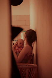 A cozy, softly lit corner with a mother reading a blog on her laptop while her baby sleeps nearby.