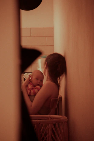 A cozy mother gently rocking her baby in a softly lit nursery with pastel colors.