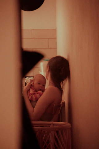 A cozy, softly lit corner with a mother reading a blog on her laptop while her baby sleeps nearby.