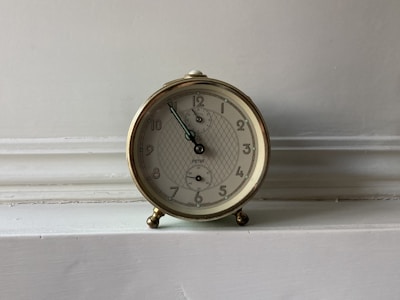A variety of colorful LED digital alarm clocks arranged neatly on a wooden shelf.