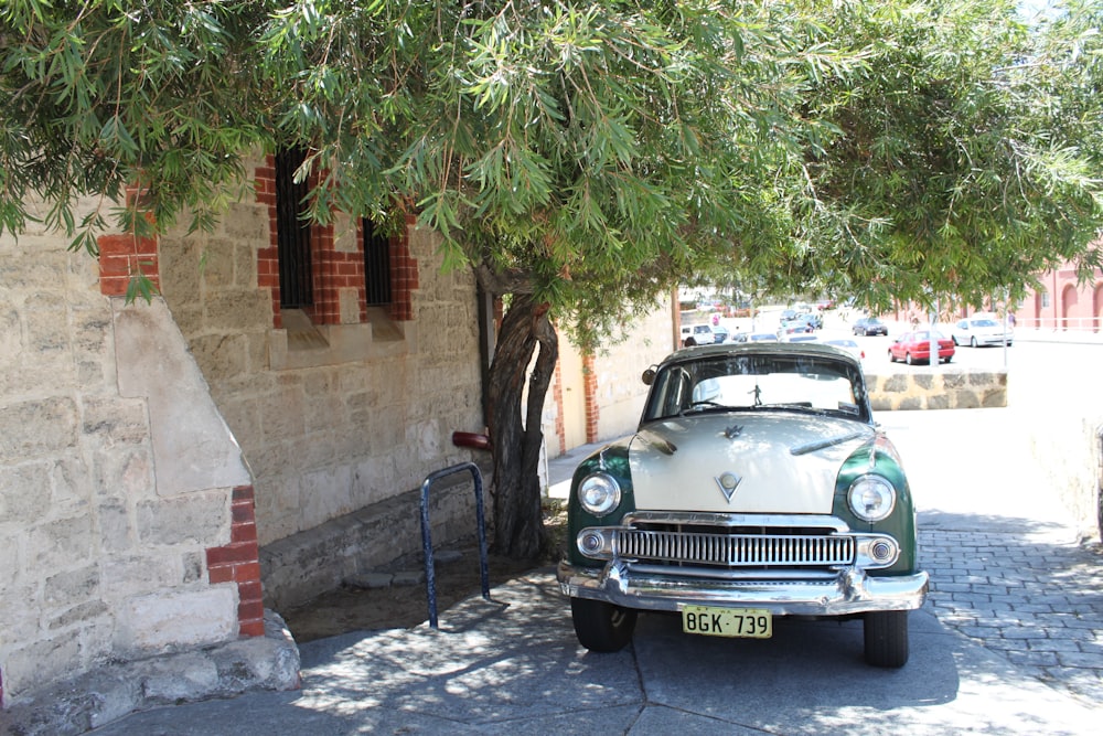 an old car is parked under a tree