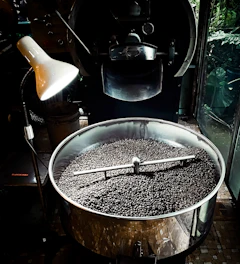 Artisanal coffee roaster with glowing beans inside, highlighting the roasting process.