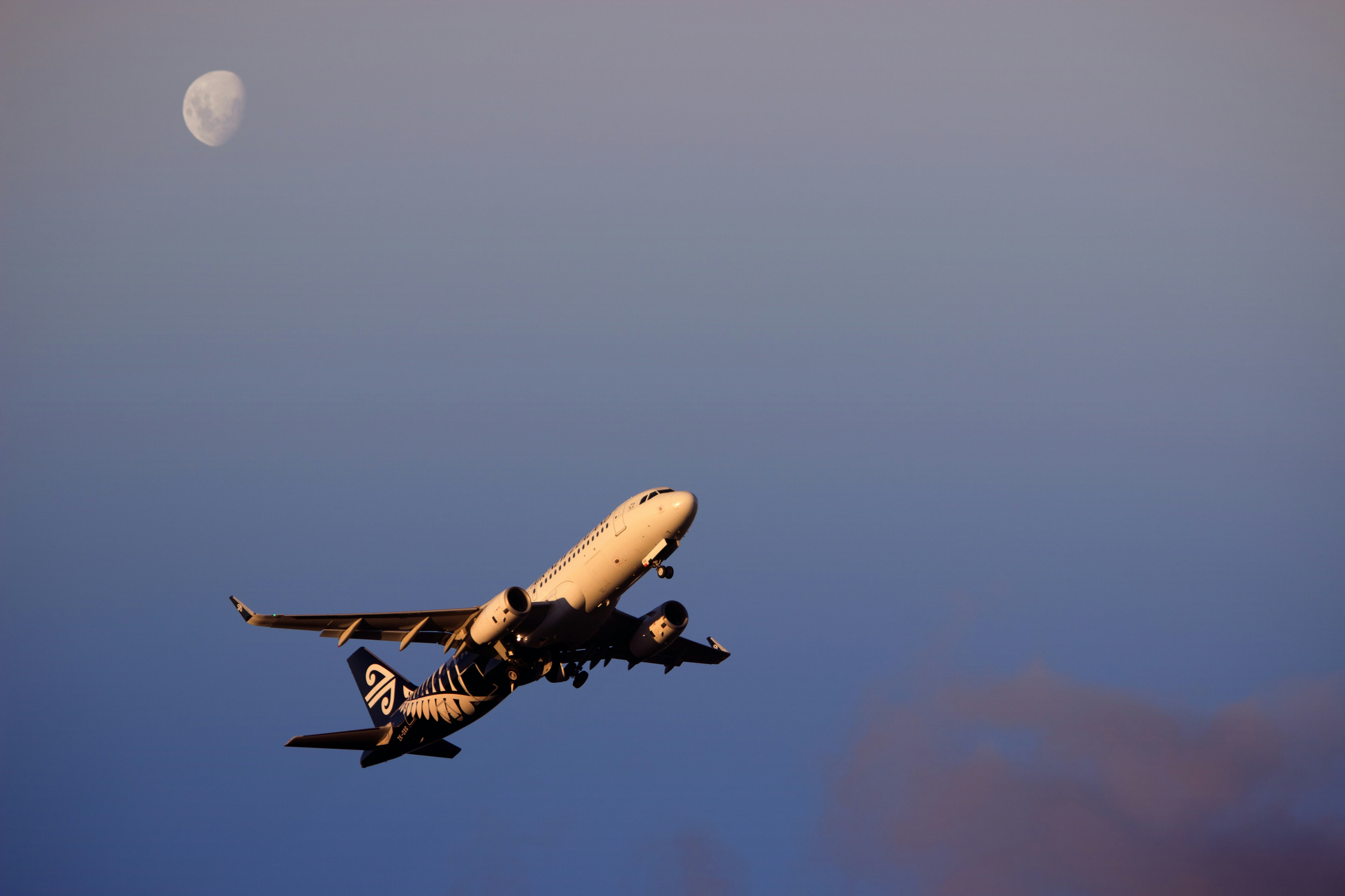 an airplane flying in the sky with the moon in the background