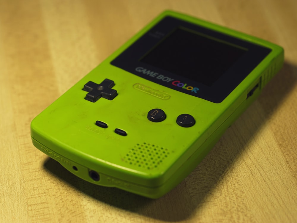 a green gameboy sitting on top of a wooden table