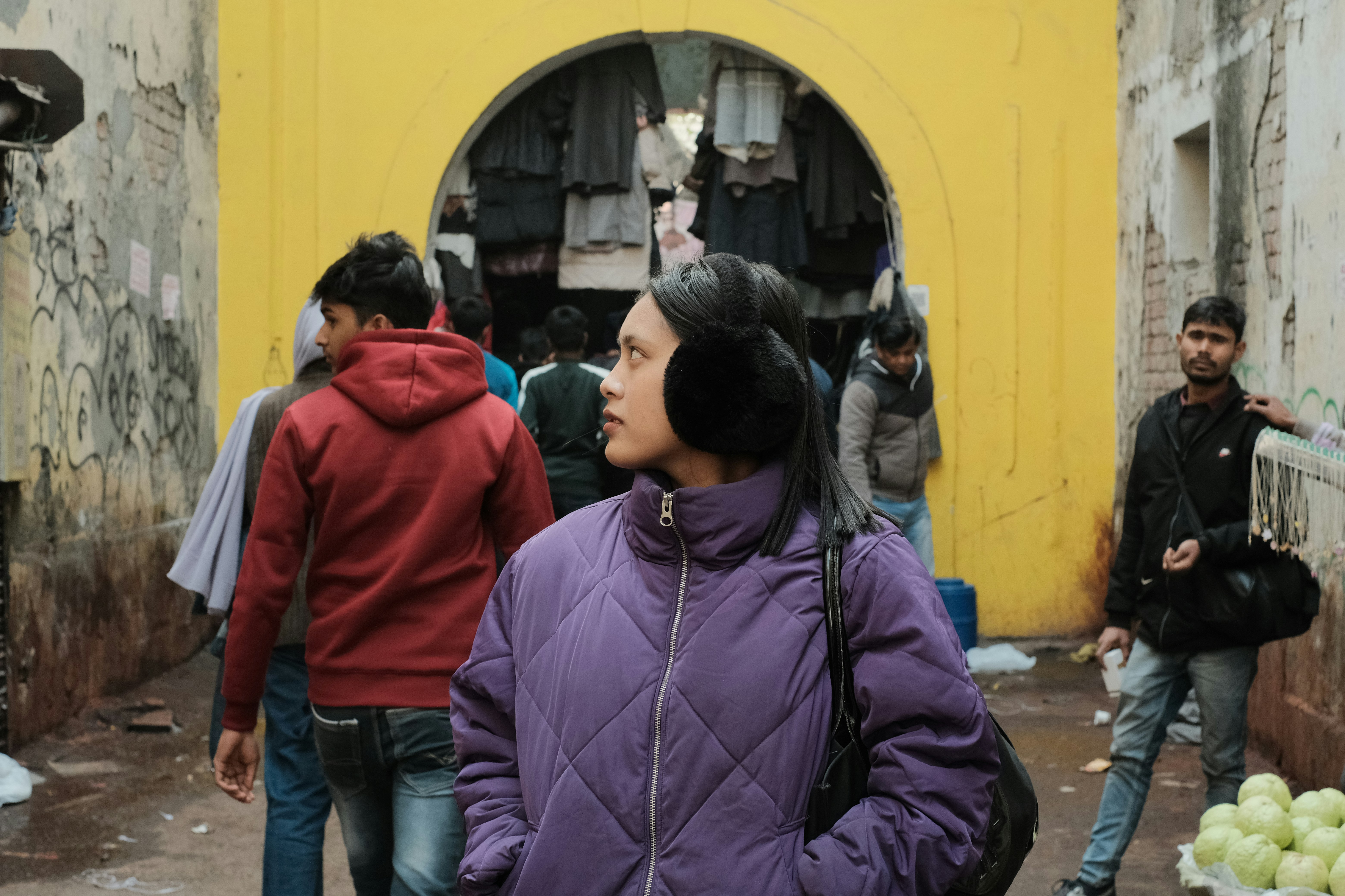 a group of people walking down a street next to a yellow building
