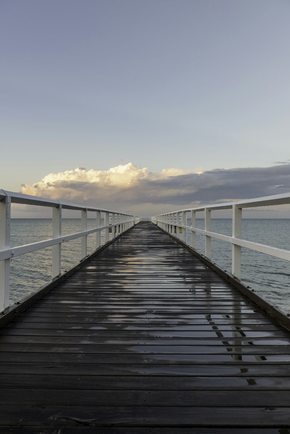 a long pier with a cloudy sky in the background