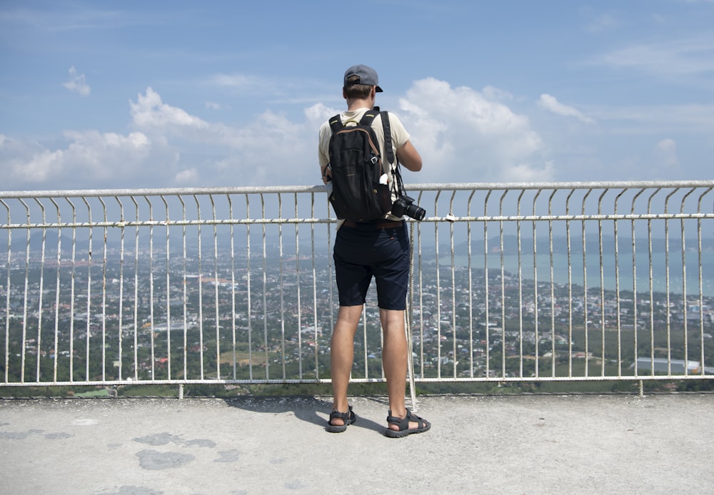 a man standing on top of a metal fence