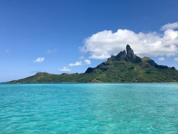 A panoramic view of a tropical island surrounded by clear blue sea under a bright sunny sky.