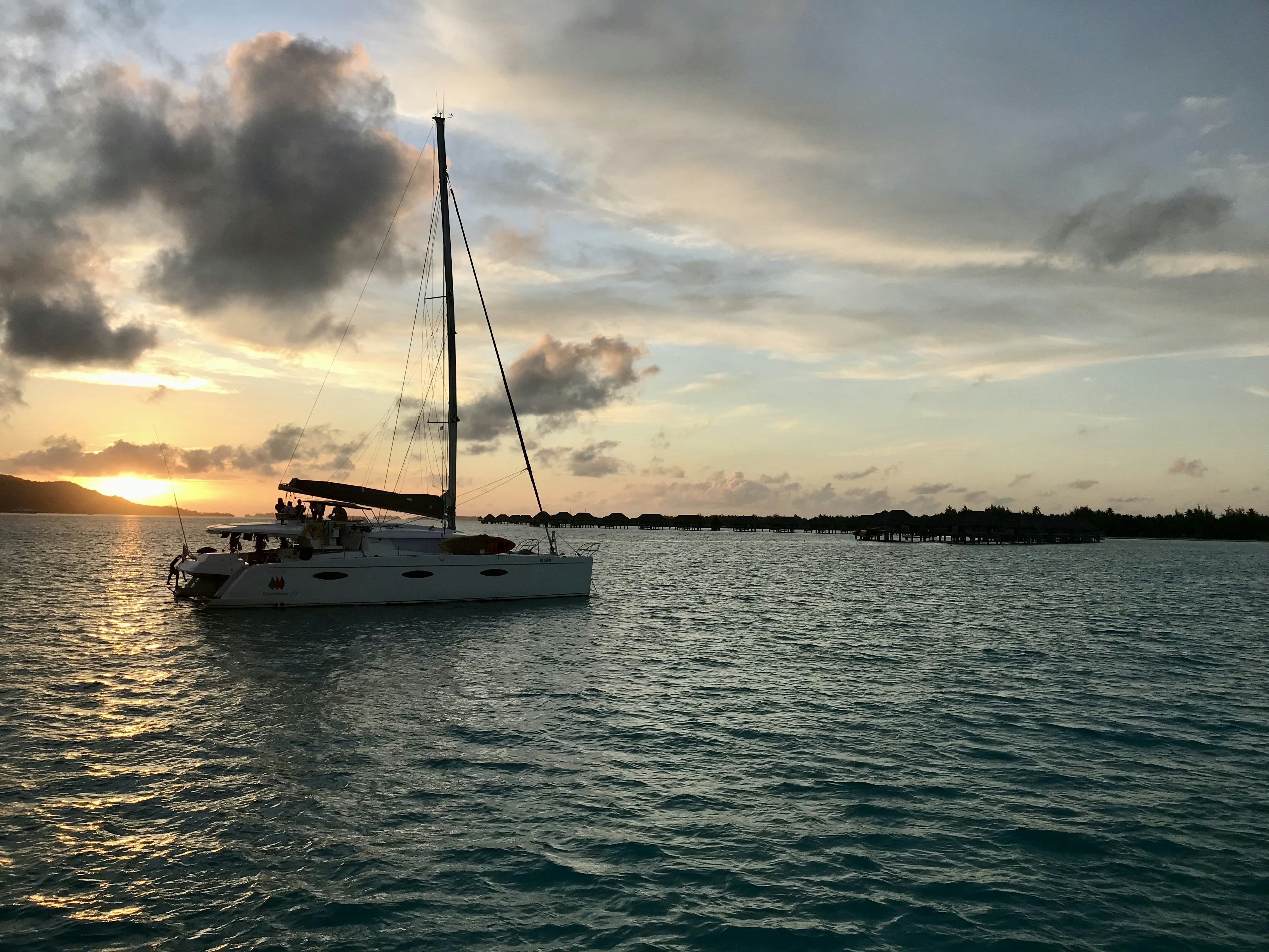 a sailboat floating in the ocean at sunset