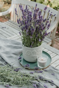 A vibrant lavender candle surrounded by fresh lavender sprigs on a rustic wooden table.