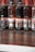 Several bottles of Sunich flavored syrups are lined up on a wooden surface. The flavors visible include chocolate and hazelnut, with labels featuring images of chocolate pieces and hazelnuts. The bottles are arranged against a brick wall background.