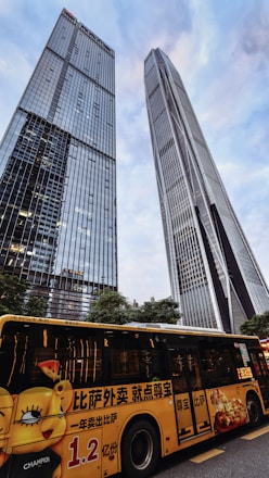 A vibrant tour bus driving past iconic Dubai skyscrapers under a clear blue sky.