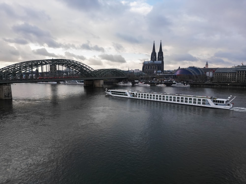 a large white boat floating on top of a river next to a bridge