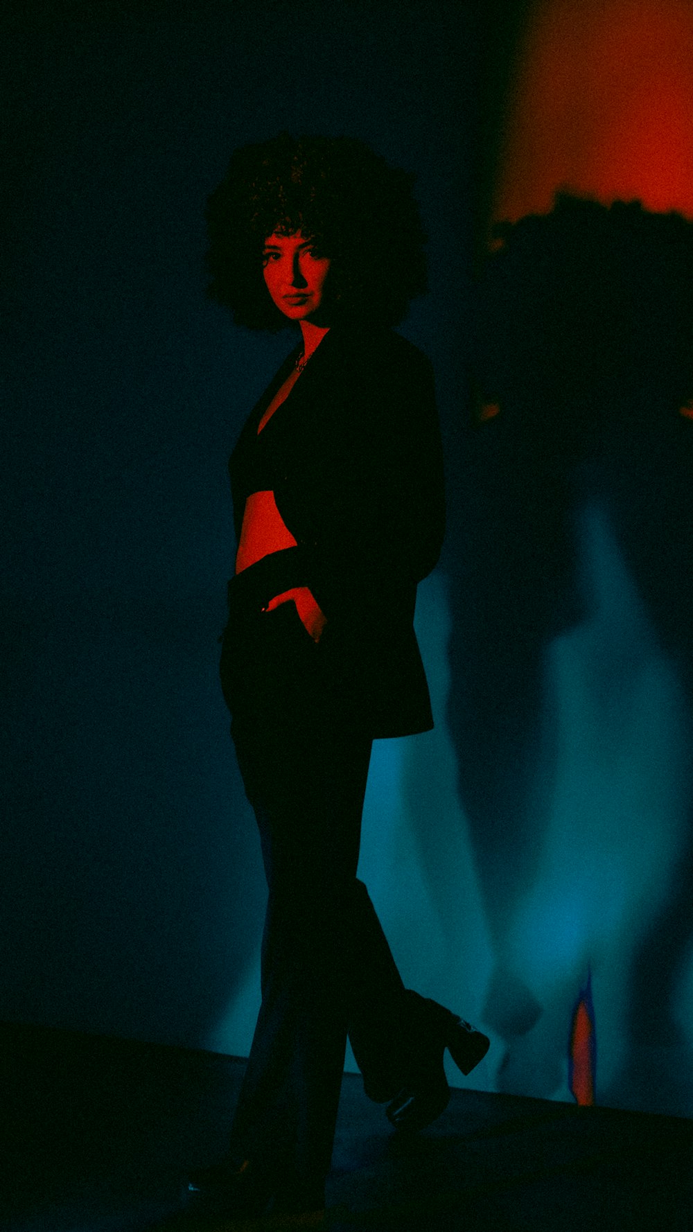 a woman standing in a dark room with a blue background