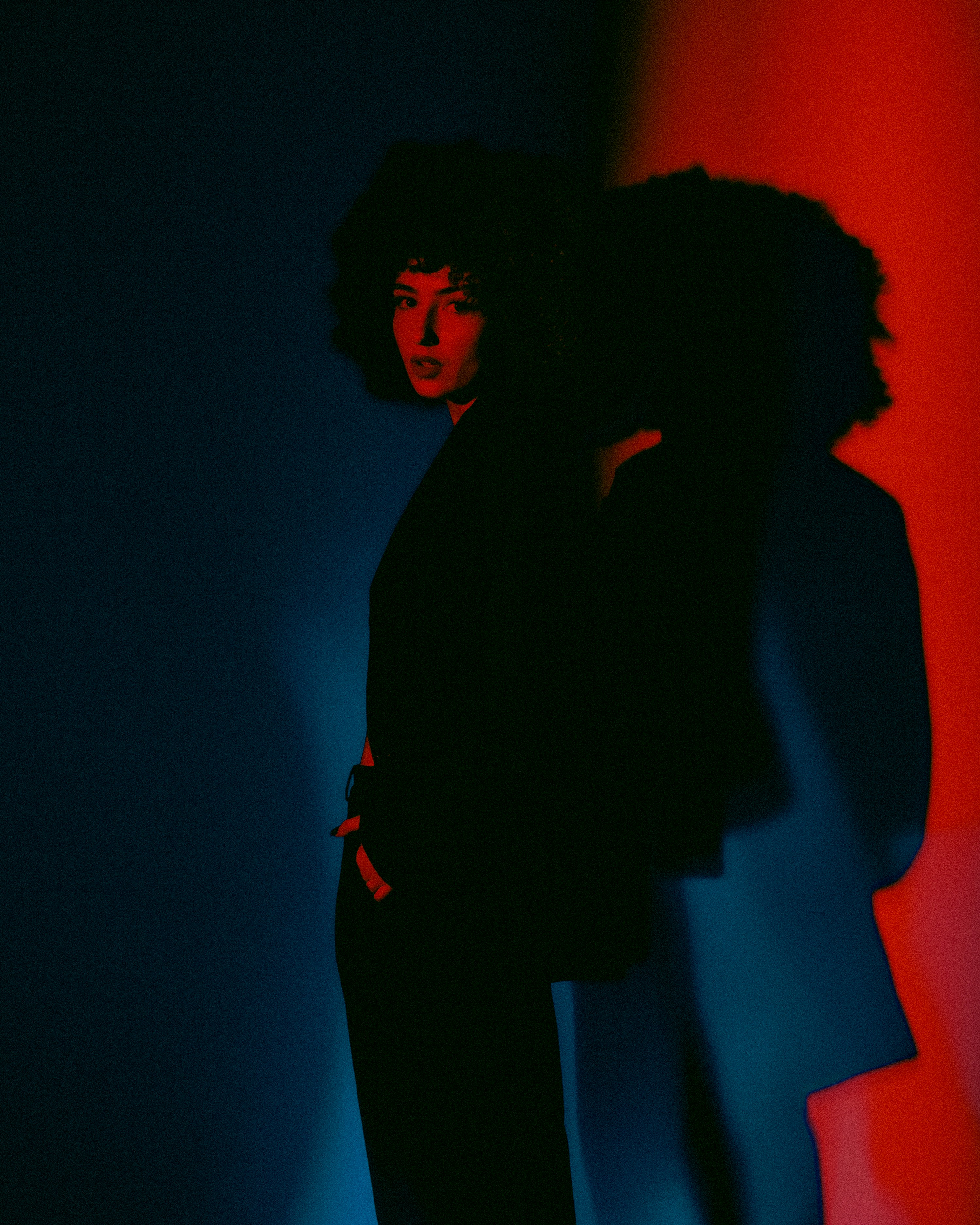 Una mujer parada frente a una pared roja y azul