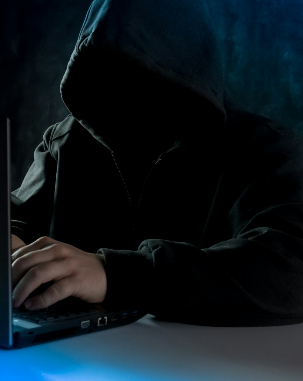 um homem em um capuz usando um computador portátil