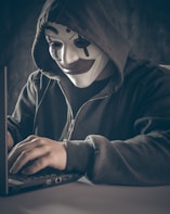 a person wearing a mask using a laptop
