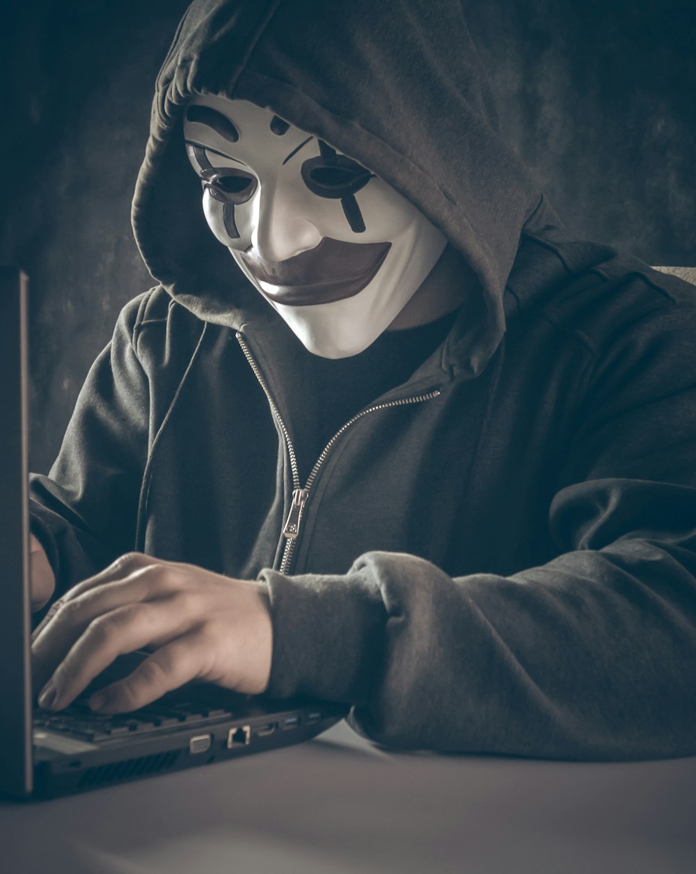 a person wearing a mask using a laptop