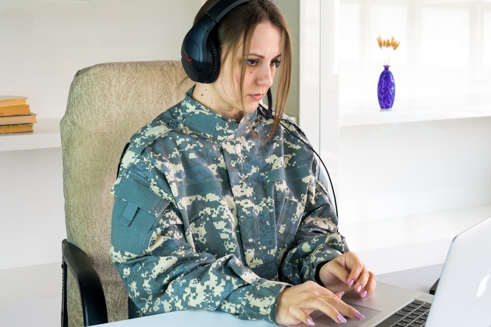 uma mulher que usa fones de ouvido sentada na frente de um computador portátil